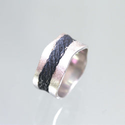 Sandblast textured silver band with black river running through. The edges of the band are waved