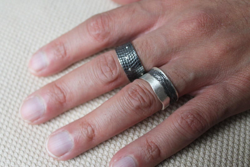 Black crocodile textured wide band with 9 white diamonds like stars in the night sky.  Seen on the middle finger of model's hand